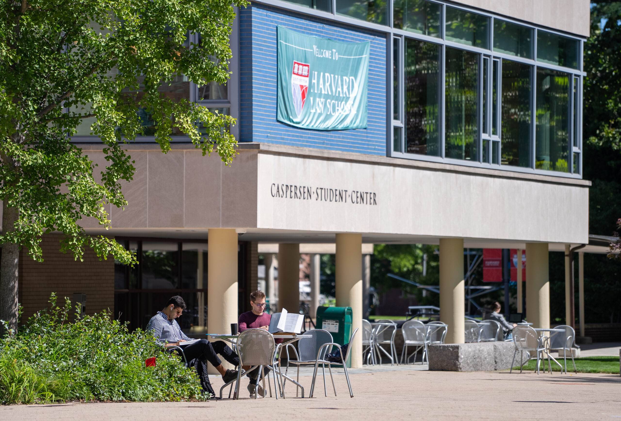 Two students studying at a table on the patio outside the campus student center on a nice day.