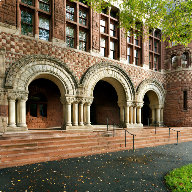 A red brick campus building with three arches.