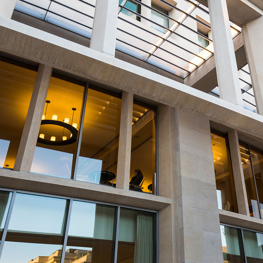 View from outside into a illuminated second floor room in a campus building.