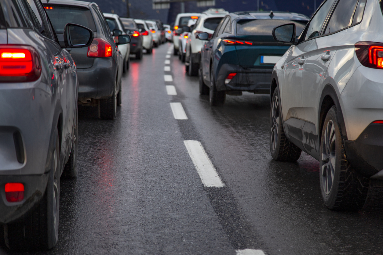 Traffic jam with a row of cars on a highway during rush hour showing red brake lights.