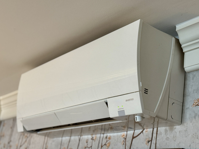 A heat pump installed on a wallpapered wall.