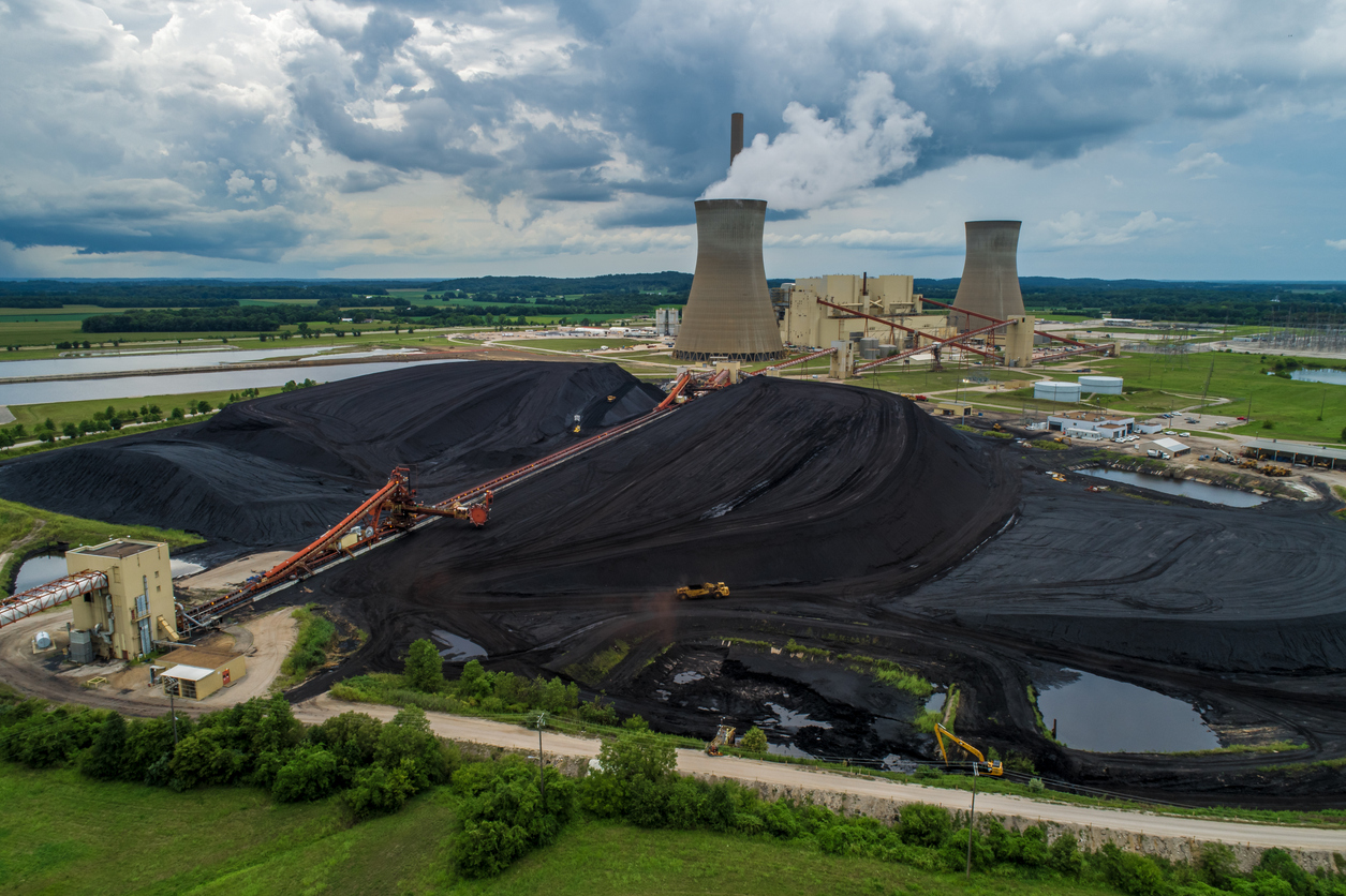 Aerial view of a power plant next to a large pile of coal.