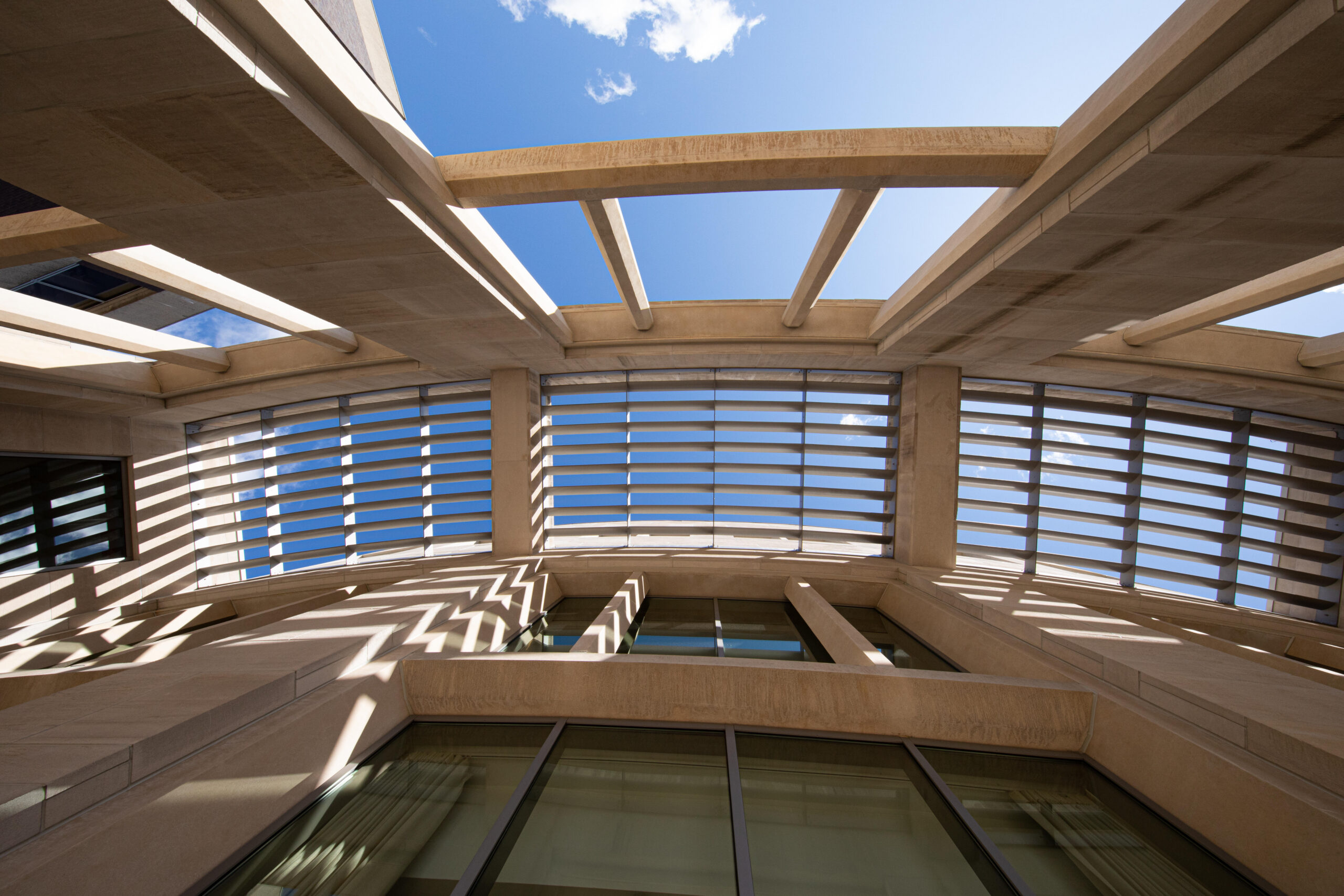 View looking up through a pergola towards a bright blue sky.